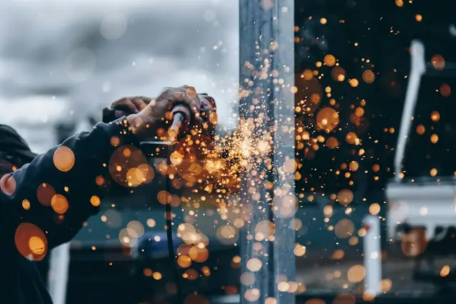 Pekerja memotong logam di lini produksi